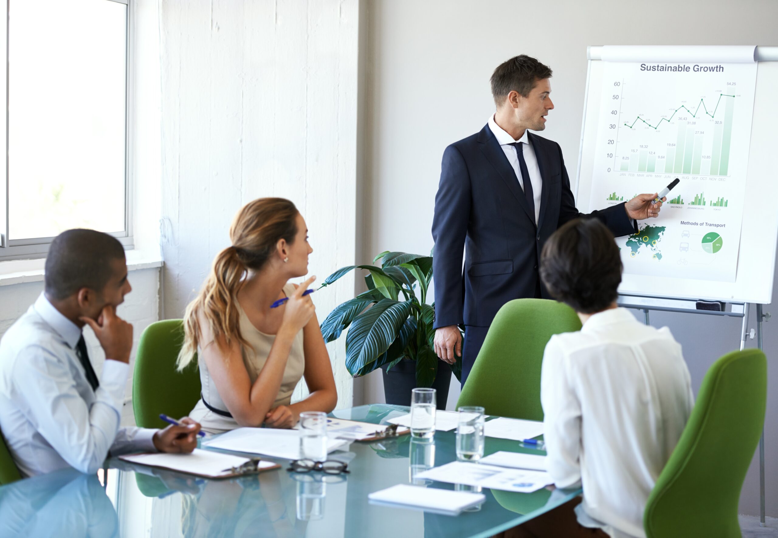 A male professional presenting business growth strategies to his team in a conference room.