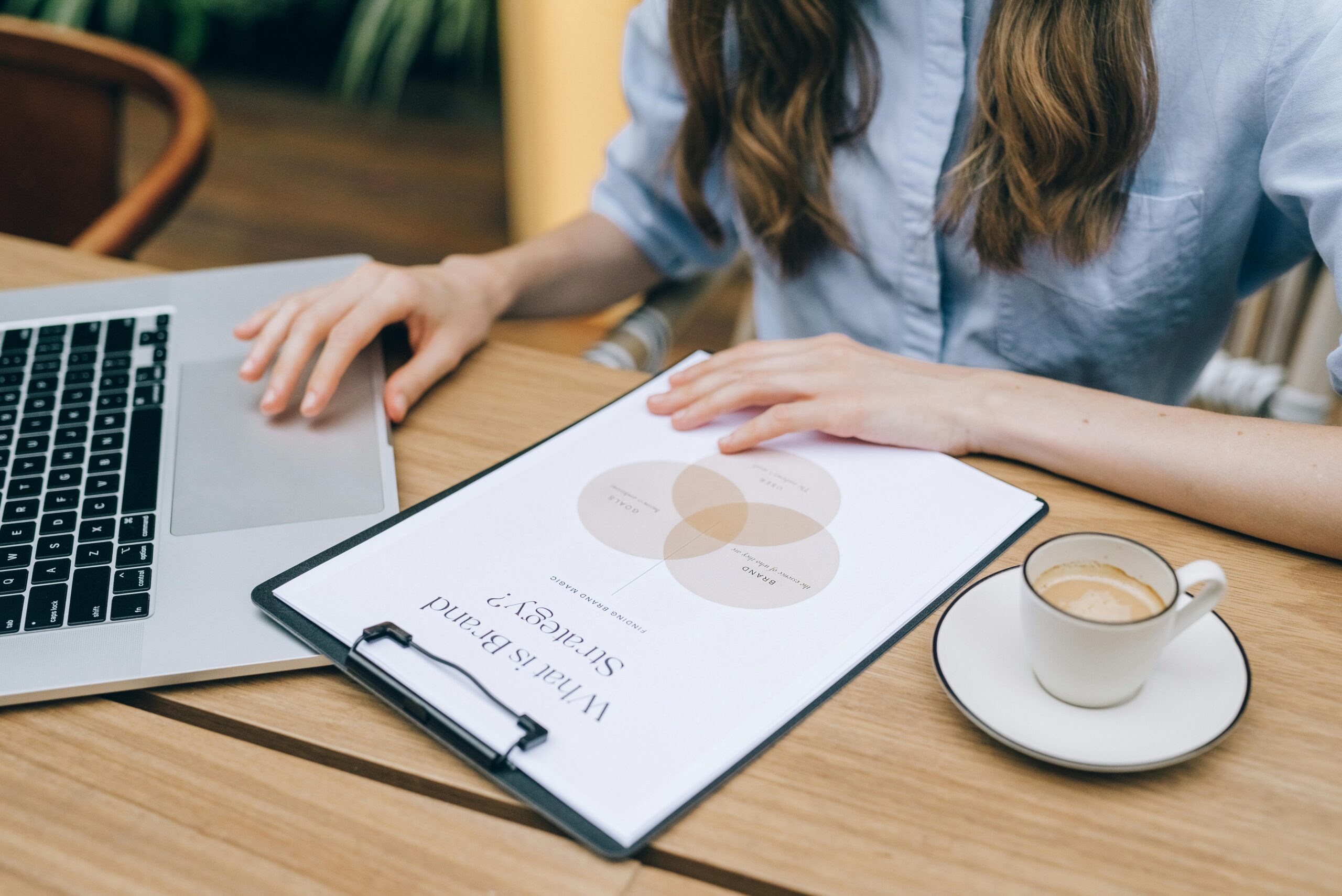 A woman mapping out brand strategy with a clipboard and laptop in front of her.